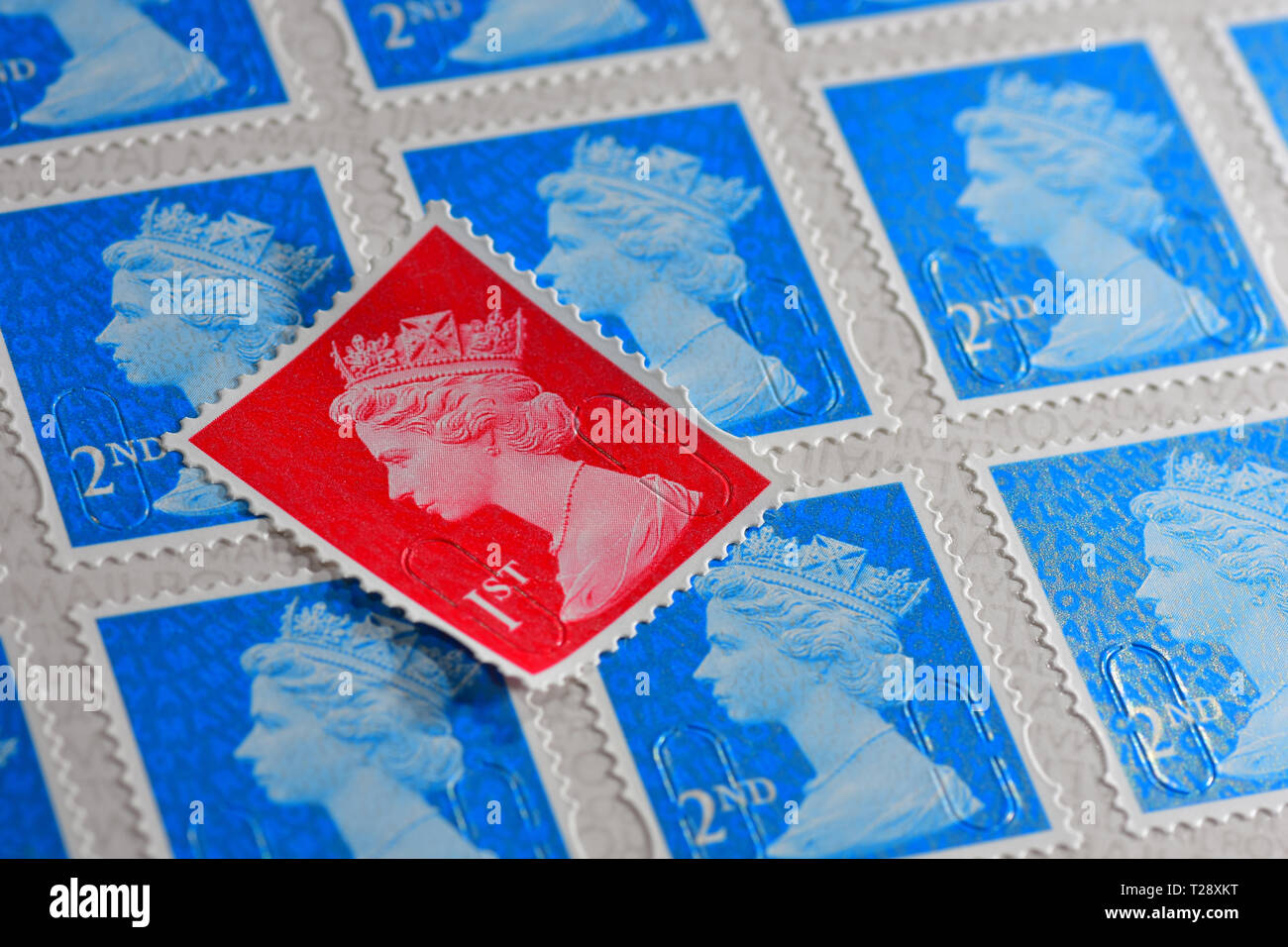 One red British 1st Class Stamp with blue 2nd class stamps Stock Photo