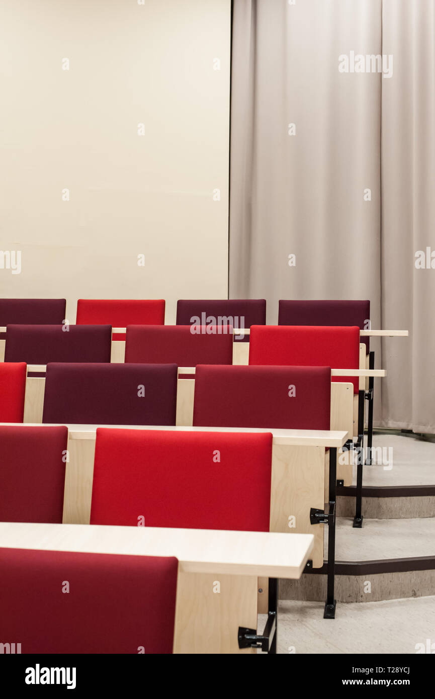 Colourful red seat covers in a university lecture theatre. Stock Photo