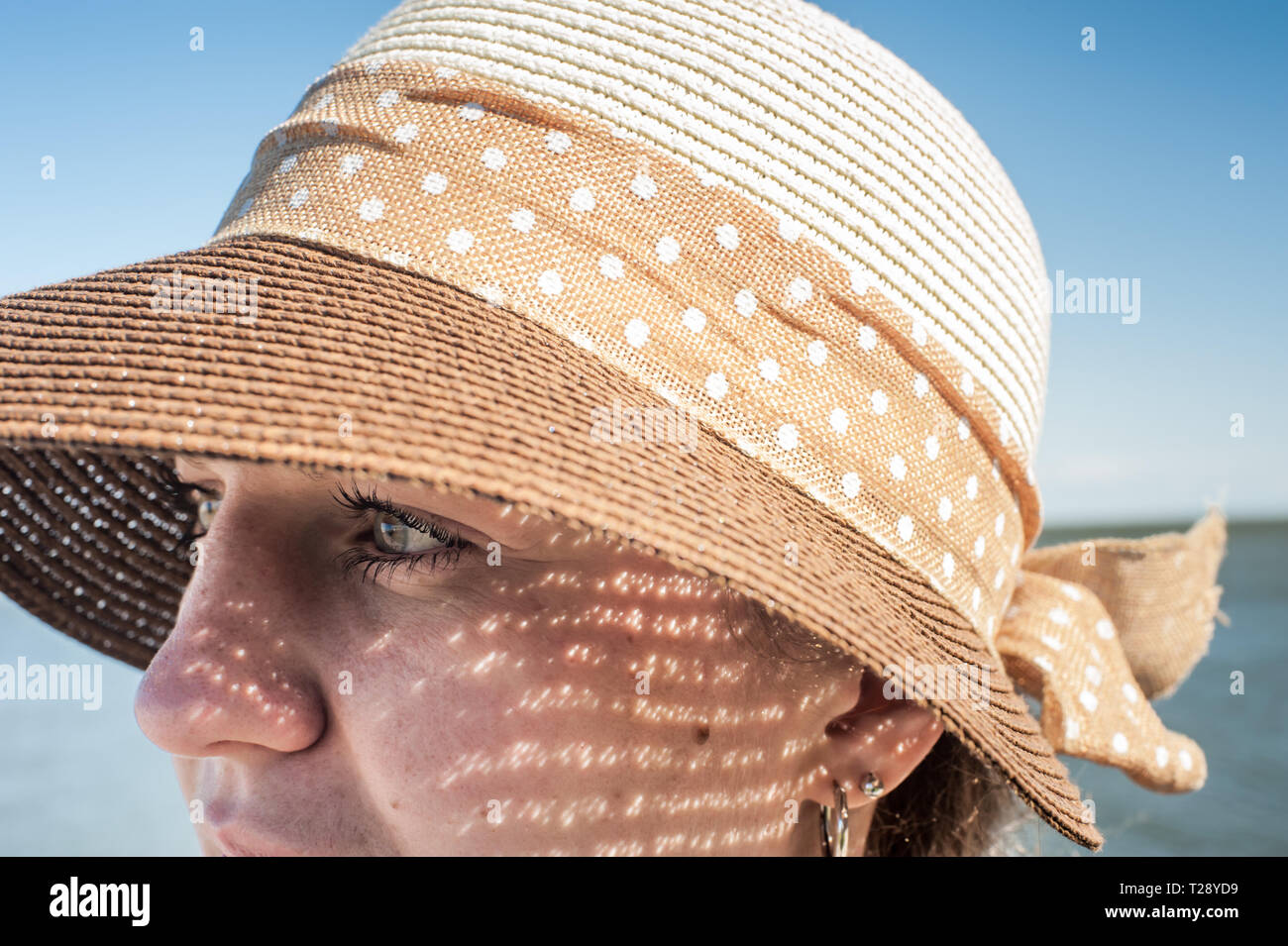Close up of a young woman wearing a hat in the sun. Stock Photo