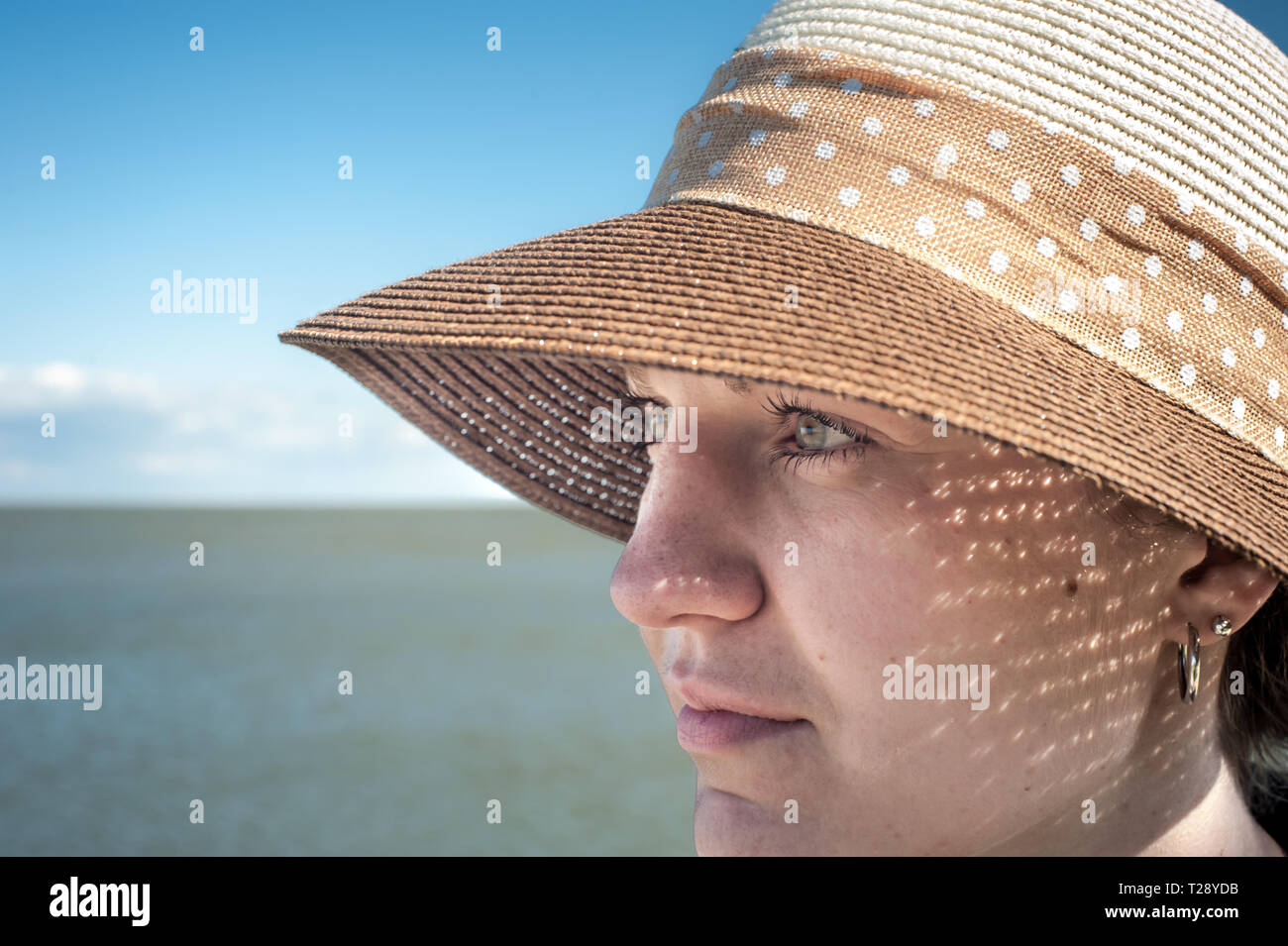 Close up of a young woman wearing a hat in the sun. Stock Photo