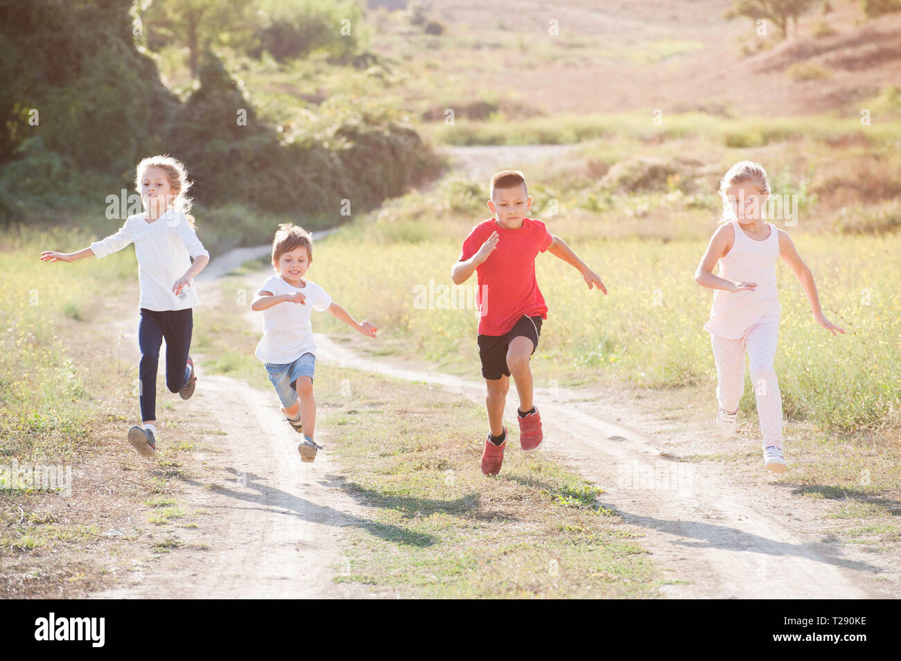 four little kids boys and girls running fast along trail outdoors leisure  pursuit Stock Photo - Alamy