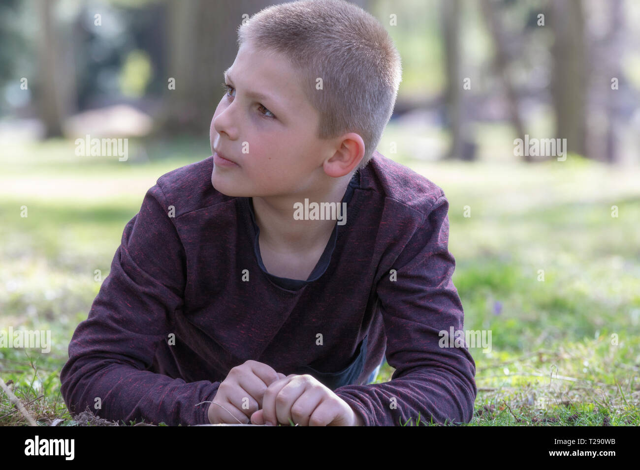 Portrait of a boy lying on the grass in the garden on a summer day looking to the side Stock Photo