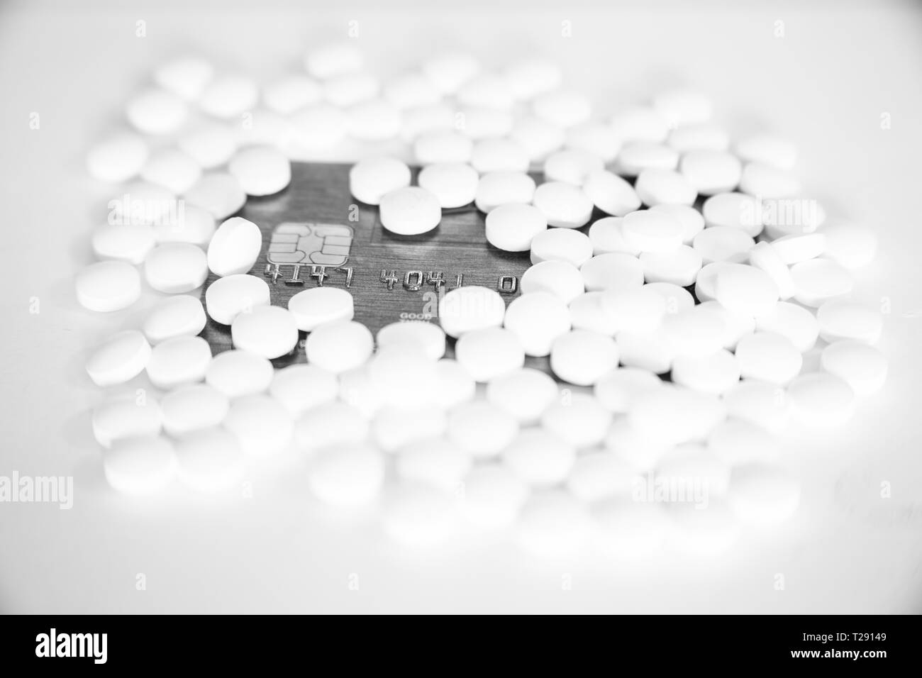 Pills sitting in a pile on top of a credit card Stock Photo