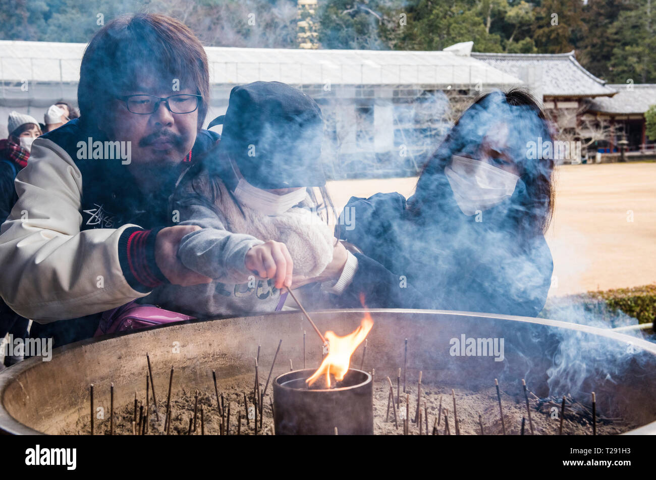 Couple helping child to light incense at the Yasaka Jinja Shrine, Gion