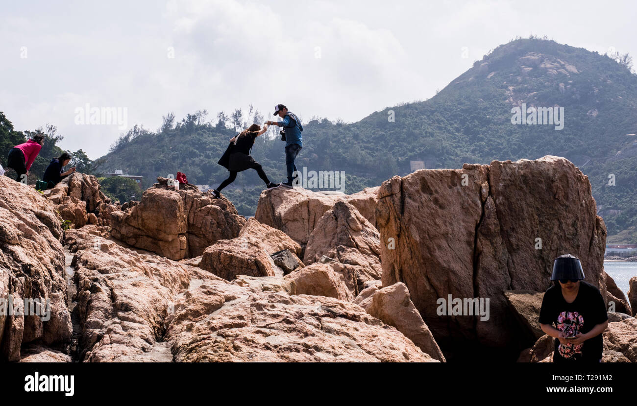 Group of people exploring rocks by sea, in the seaside village of Stanley, Hong Kong Stock Photo