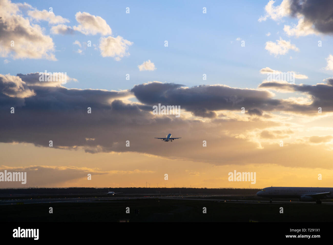 Passanger airplane is flying up in front of bright dusk Stock Photo