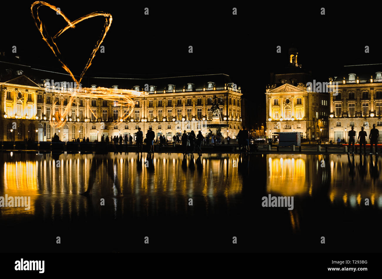 Bordeaux, France - September 15, 2018 : Fire juggler draws a heart of fire at the water mirror in front of place de la bourse illuminated at night Stock Photo