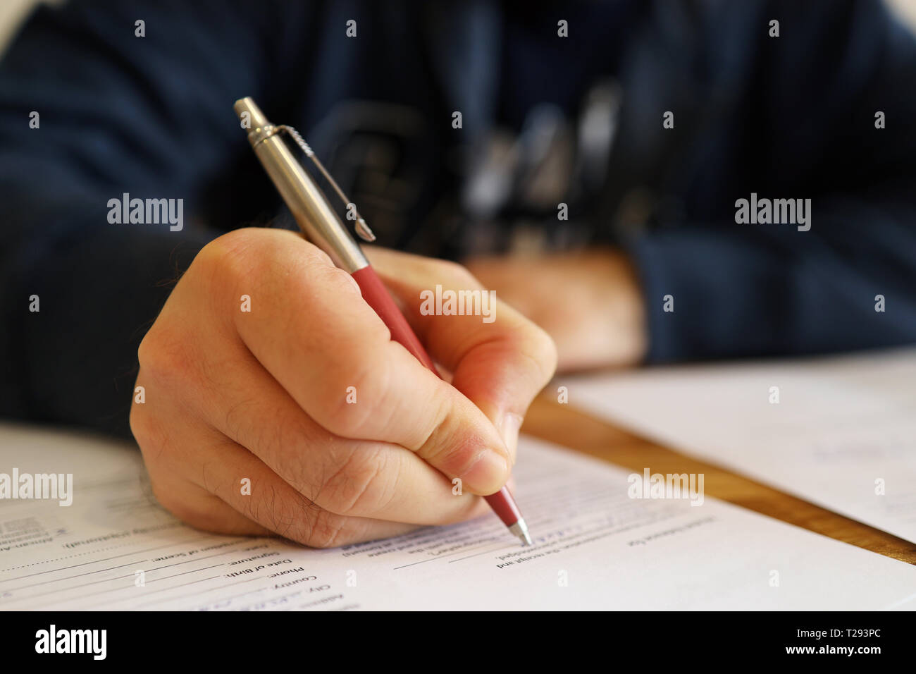 Man hand with pen. Close up of the hand of a man fill in a contract. Selective focus on hand. Blurred agreement content Stock Photo