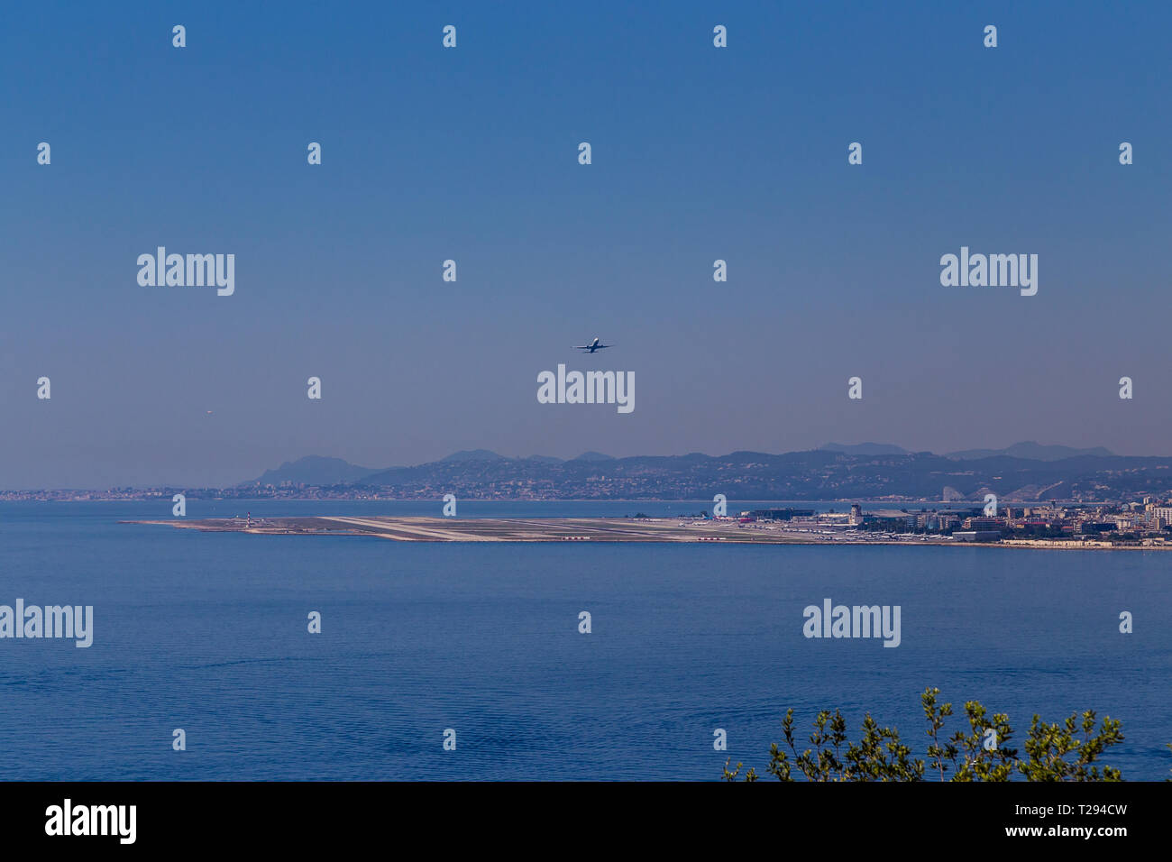 A plane takes off from Nice Côte d'Azur Airport and gains altitude over the sea. ICAO LFMN Stock Photo