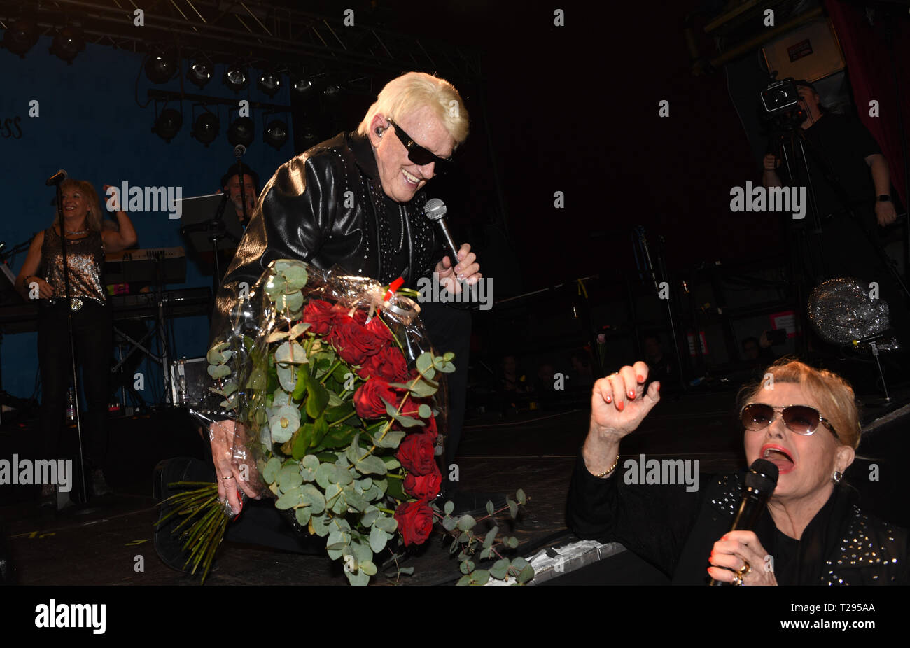 Cologne, Germany. 30th March 2019.  The singer Heino kneels on his farewell tour 'und Tschüss' (and bye) He was presented with a bouquet of red roses by his wife Hannelore at his last concert in Germany, in the 'Live Music Hall' with a microphone on stage. Photo: Horst Ossinger//dpa Credit: dpa picture alliance/Alamy Live News Stock Photo
