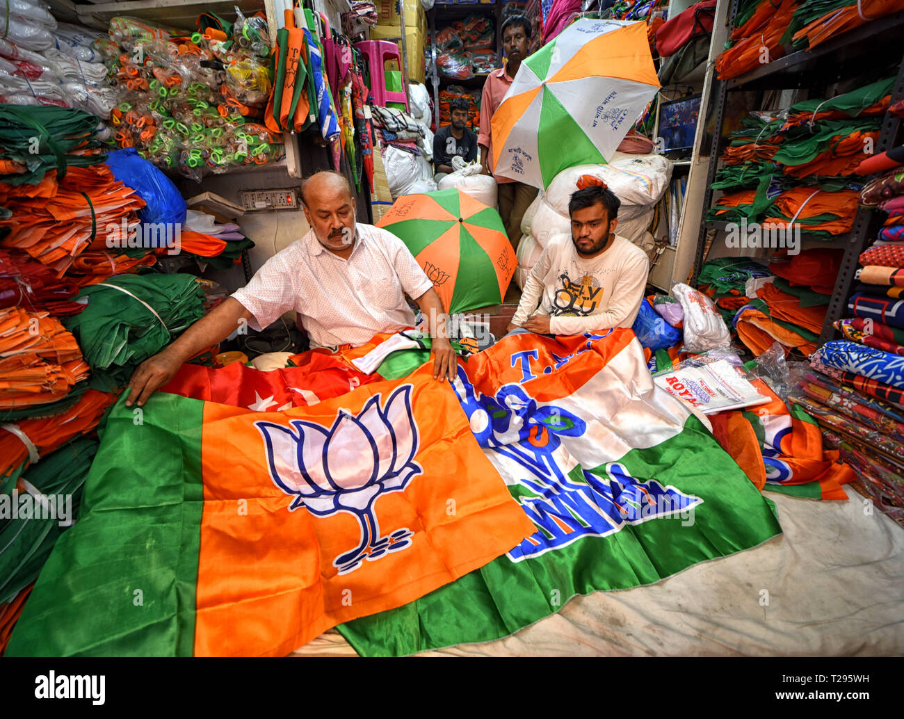 Kolkata, India. 30th March 2019. A shop owner seen displaying Indian Political party's Flag, Umbrella, Caps All India Trinamool Congress (TMC), Bharatiya Janata Party (BJP), National Congress, CPIM (Communist Party) ahead of the General Election of India 2019. Credit: SOPA Images Limited/Alamy Live News Stock Photo