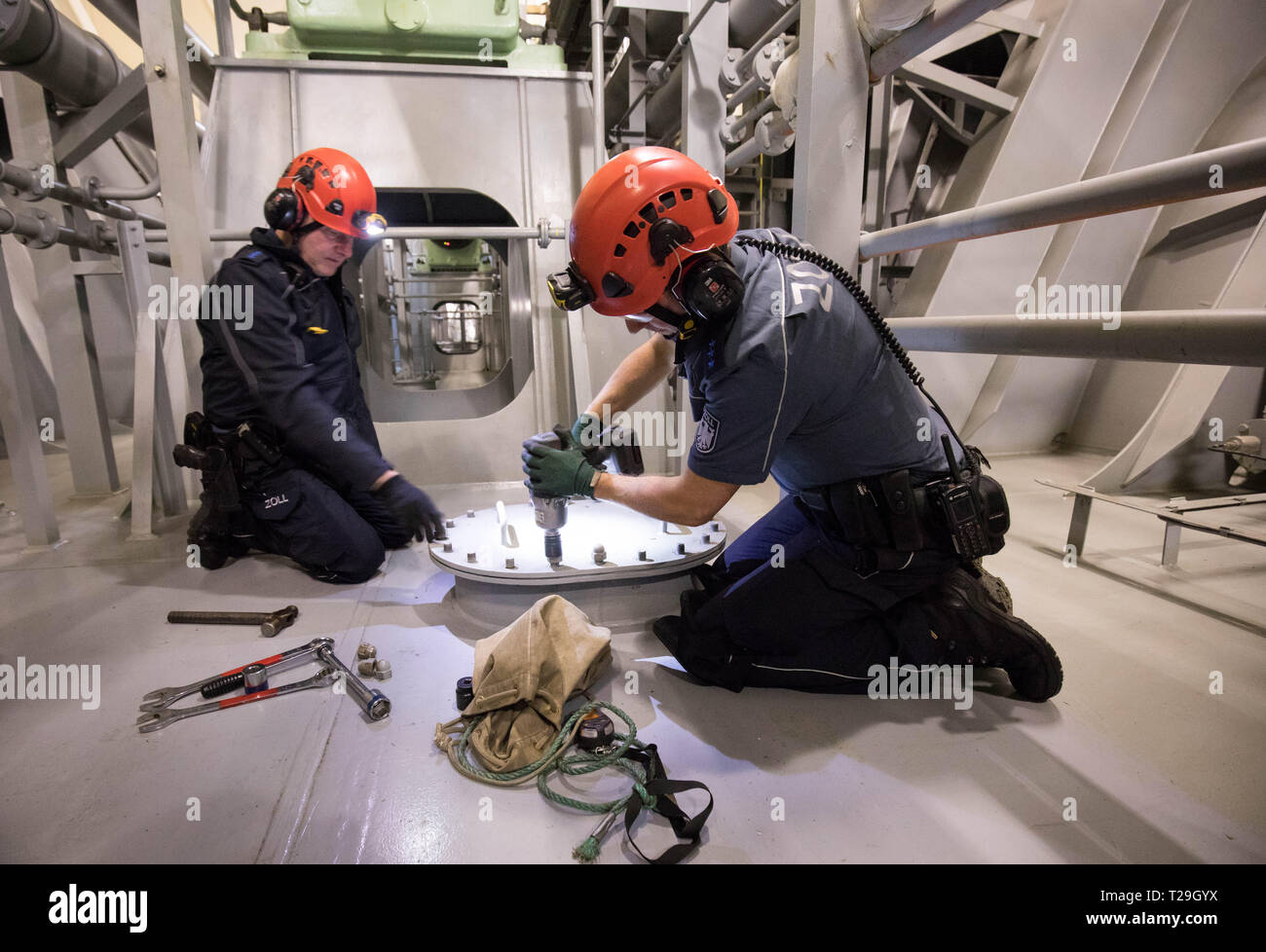 Hamburg, Germany. 22nd Mar, 2019. Customs officers of the Köhlbrand control group open the hatch to a so-called suitcase dam between the ballast tanks in the engine room of a container ship during an inspection. Customs personnel are tracking down illegal imports. (to dpa 'Smuggled Goods Search on Megafreighters - Officials as Miners and Surgeons') Credit: Christian Charisius/dpa/Alamy Live News Stock Photo