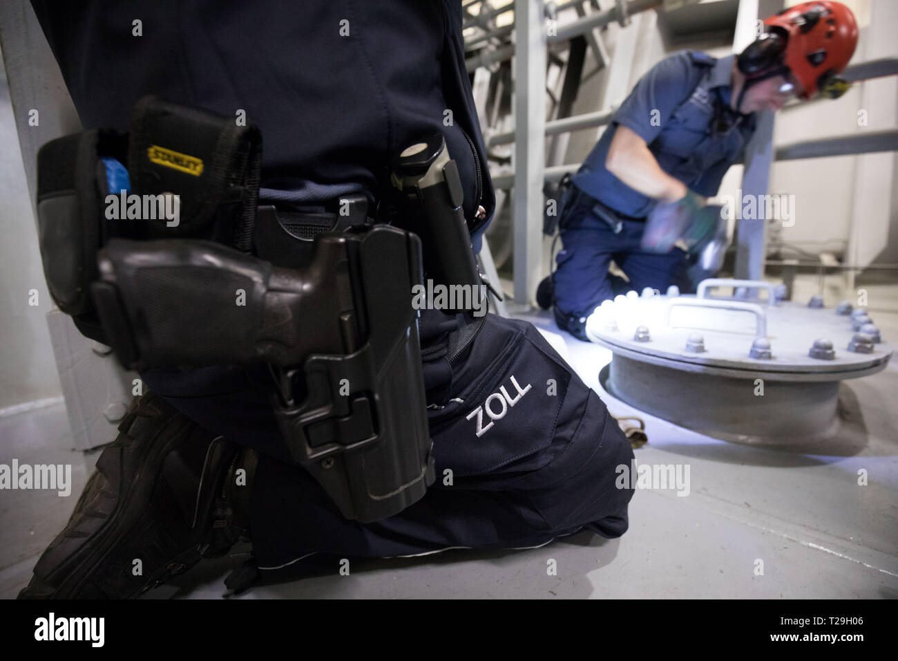 Hamburg, Germany. 22nd Mar, 2019. Customs officers of the control group Köhlbrand open the hatch to a so-called cofferdam between the ballast tanks in the engine room of a container ship during an inspection. Customs personnel are tracking down illegal imports. (to dpa 'Smuggled Goods Search on Megafreighters - Officials as Miners and Surgeons') Credit: Christian Charisius/dpa/Alamy Live News Stock Photo