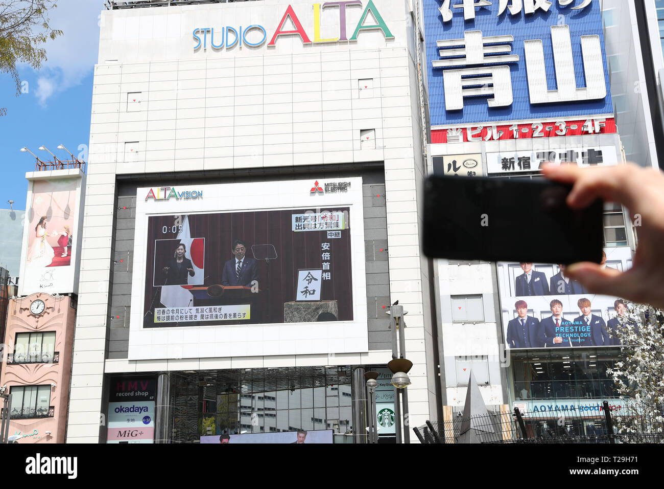 Tokyo, Japan. 1st Apr, 2019. People watch a large screen showing Japanese Prime Minister Shinzo Abe's announcement about the name of the new Imperial era, 'Reiwa,' in Tokyo, Japan on April 1, 2019. The Japanese government officially announced the country's next era will be known as the 'Reiwa' era on Monday, a month before Crown Prince Naruhito ascends the throne following Emperor Akihito's abdication. Credit: Yohei Osada/AFLO/Alamy Live News Stock Photo
