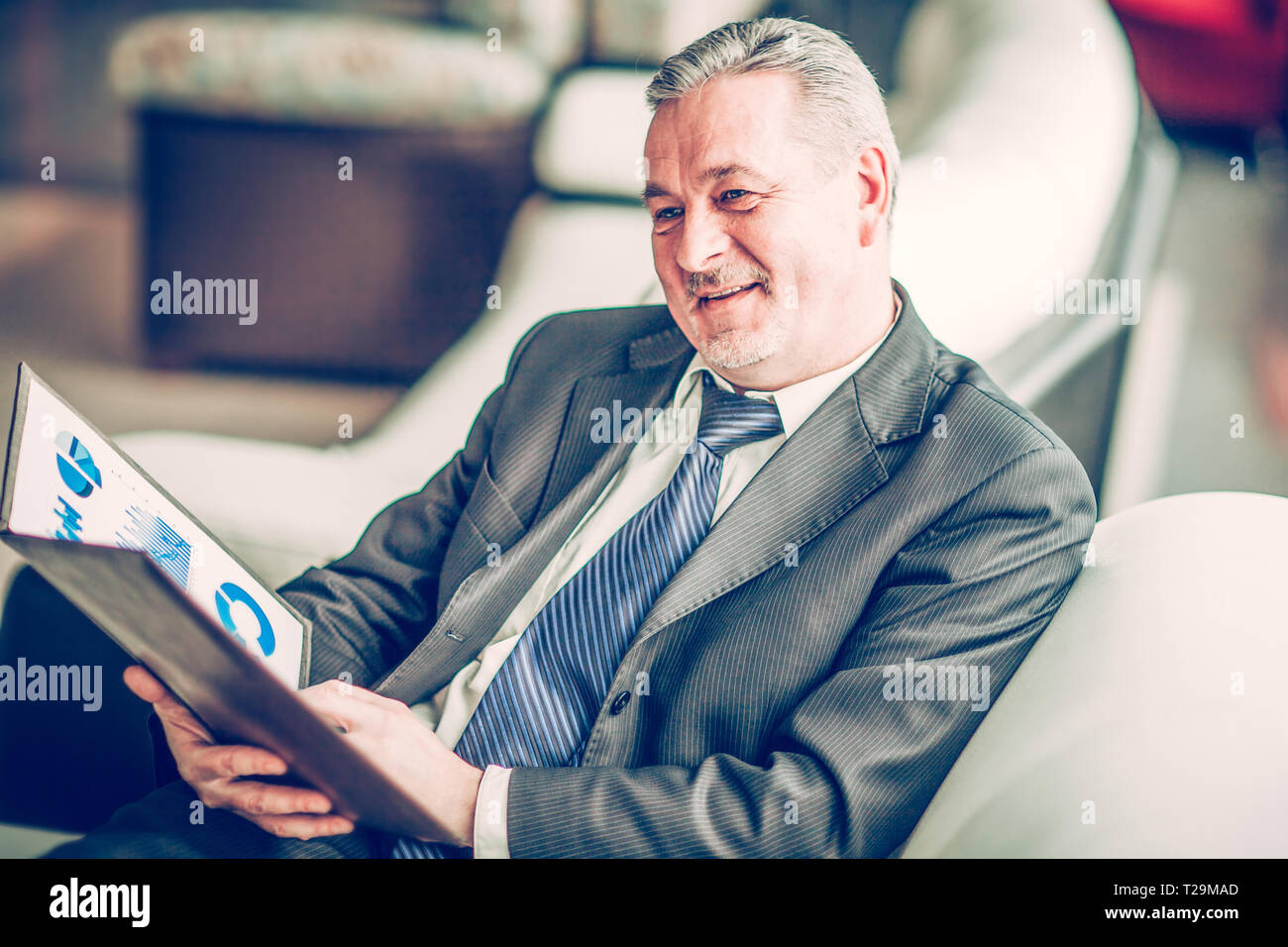 experienced financier with financial charts sitting in the chair Stock Photo