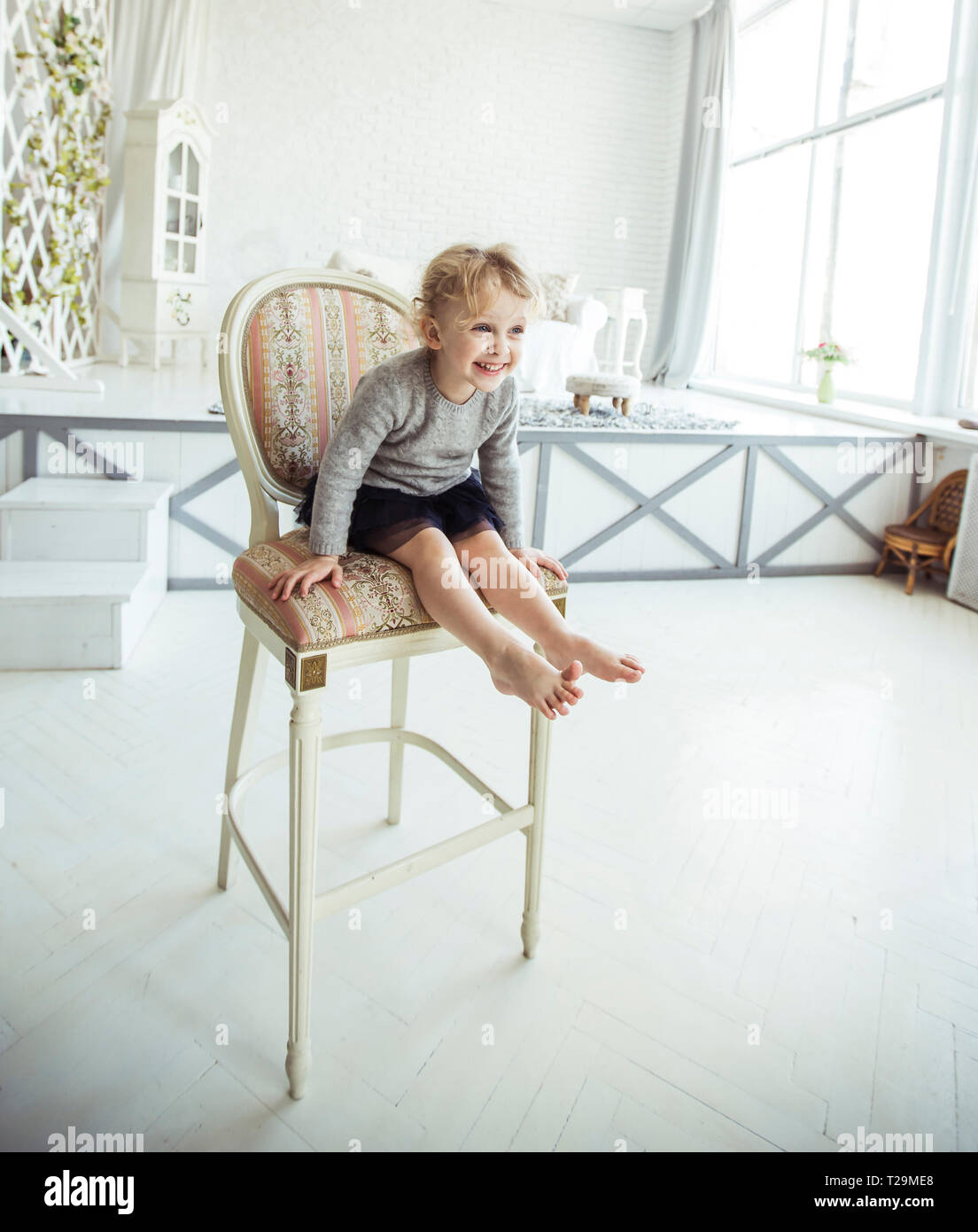portrait of a happy five year old girl sitting on a chair in the ...