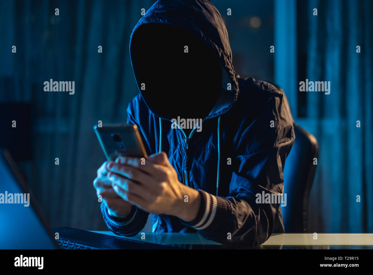Anonymous hacker programmer uses a laptop to hack the system in the dark. Creation and infection of malicious virus. The concept of cybercrime and hac Stock Photo