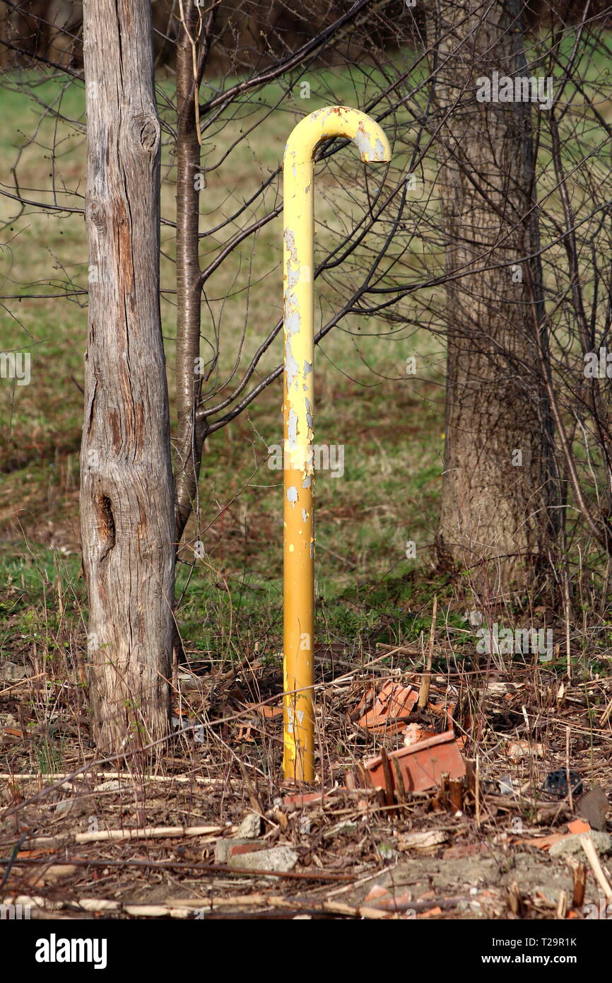 Yellow metal candy cane shaped vent relief pipe with cracked paint