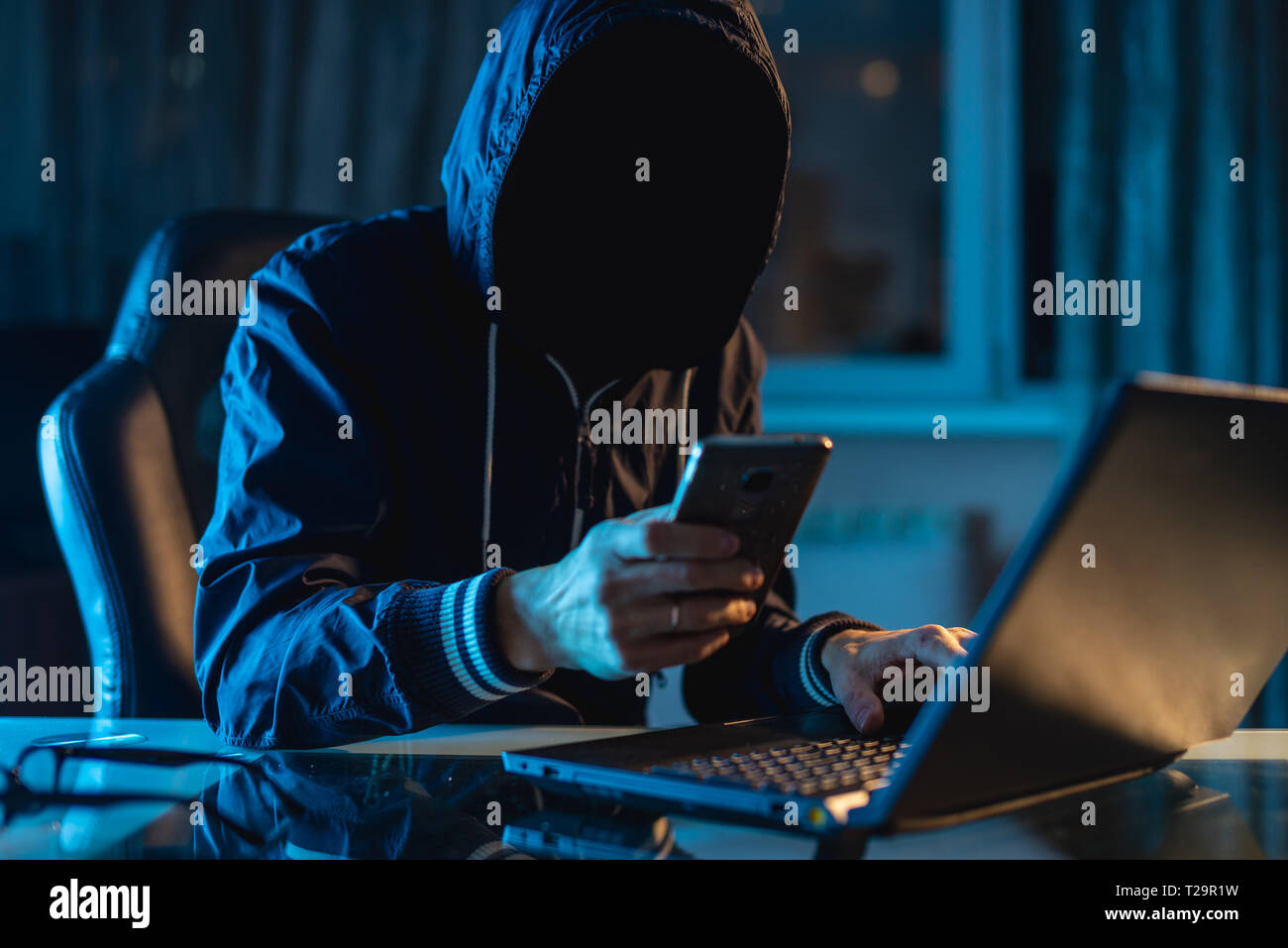 Anonymous hacker programmer uses a laptop to hack the system in the dark. Creation and infection of malicious virus. The concept of cybercrime and hac Stock Photo