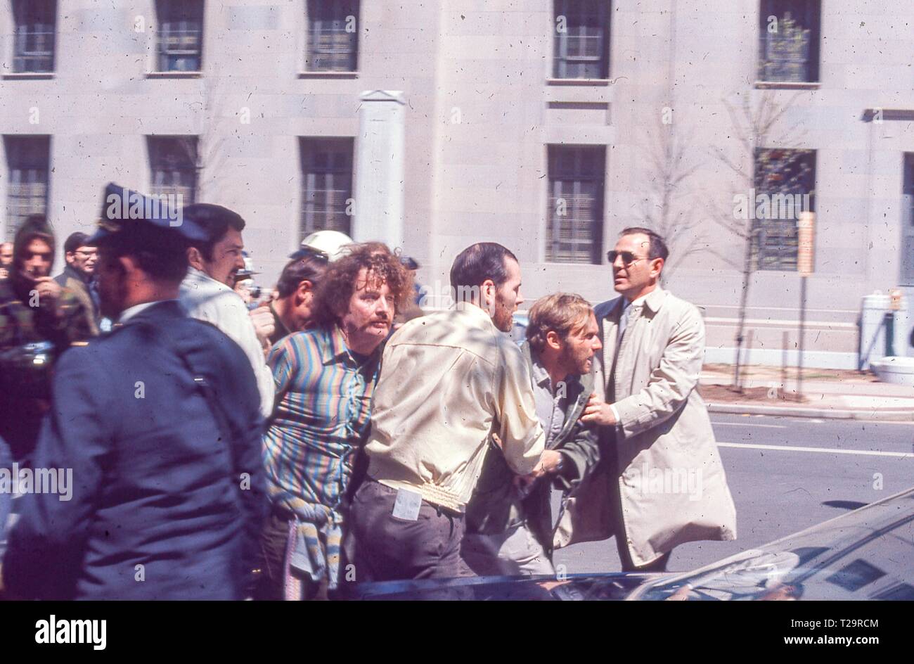 During the May Day protests against the Vietnam War in Washington, DC a protester lunges forward as he is retrained by two men in plain clothing, possibly plain-clothes law enforcement, 1971. () Stock Photo