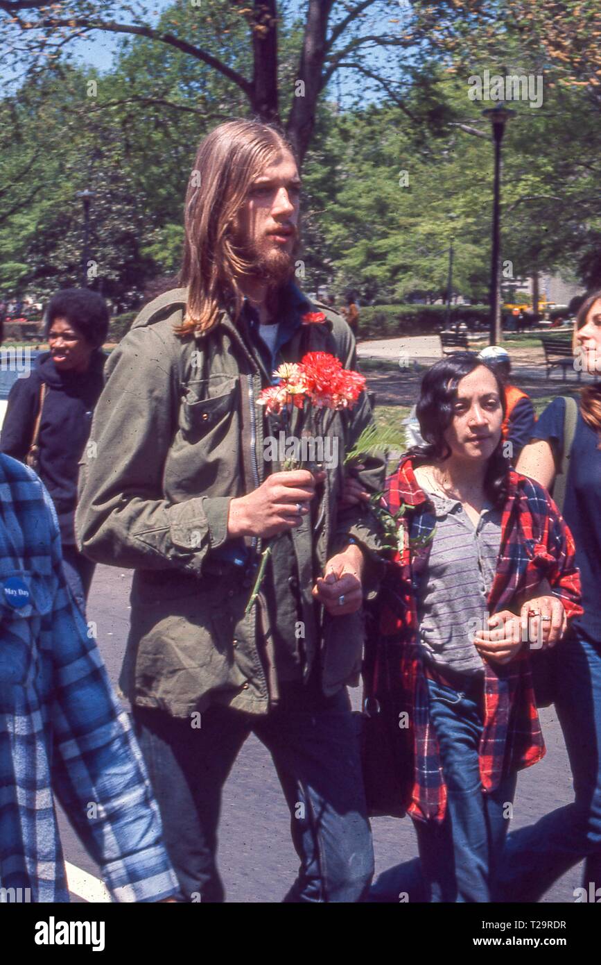 During the May Day protests against the Vietnam War in Washington, DC, protestors in hippie attire march hand in hand, as one man holds a vase of flowers, 1971. () Stock Photo