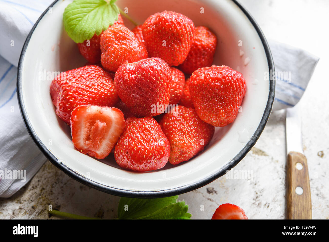 Ripe summer red strawberry in bowl at windowsill Stock Photo