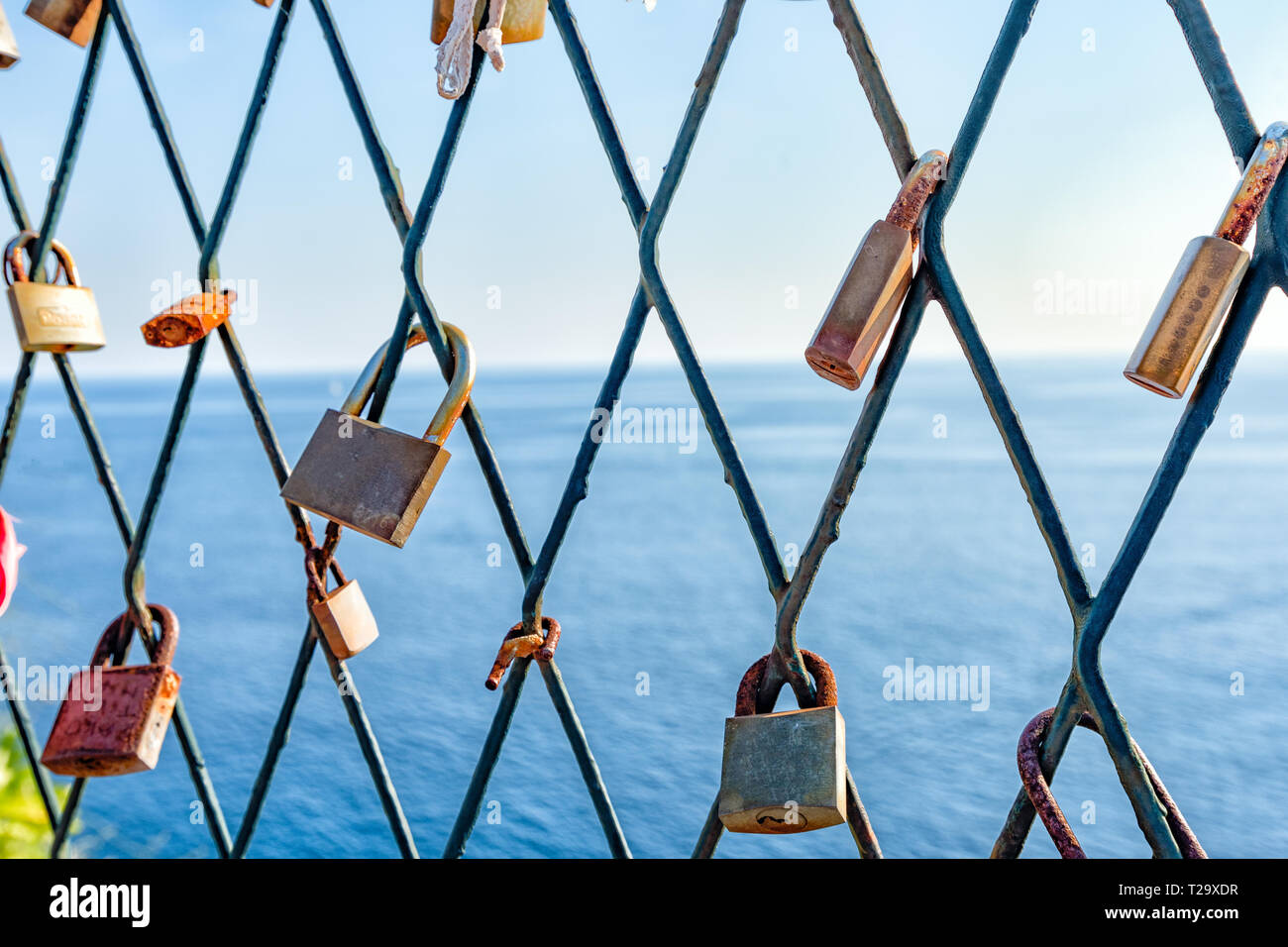 Locks on a bridge on a background of blue sea and a symbol of eternal ...