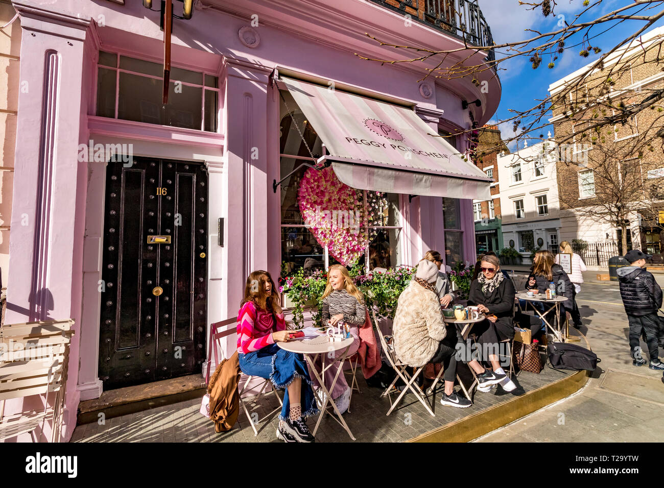 People sitting outside Peggy Porschen Cakes, in Belgravia , a cake shop known for its striking pastel pink exterior, London, UK Stock Photo