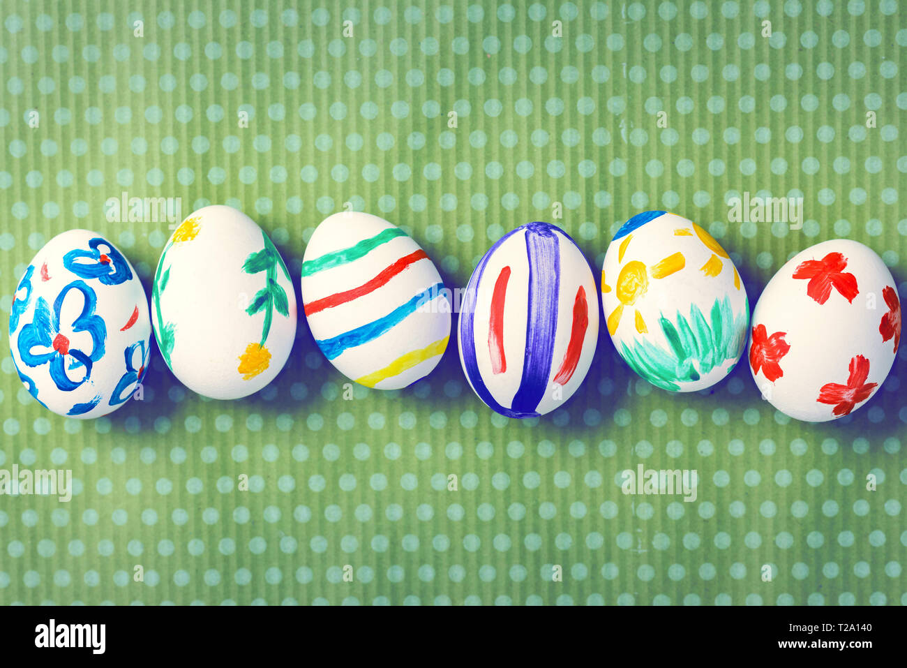 Painted Easter eggs on a green background with white polka dots. Toned image. Beautiful holiday card. Space for text. Happy easter. Stock Photo
