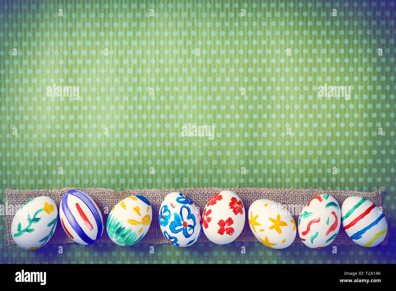 Painted Easter eggs on a green background with white polka dots. Toned image. Beautiful holiday card. Space for text. Happy easter. Stock Photo