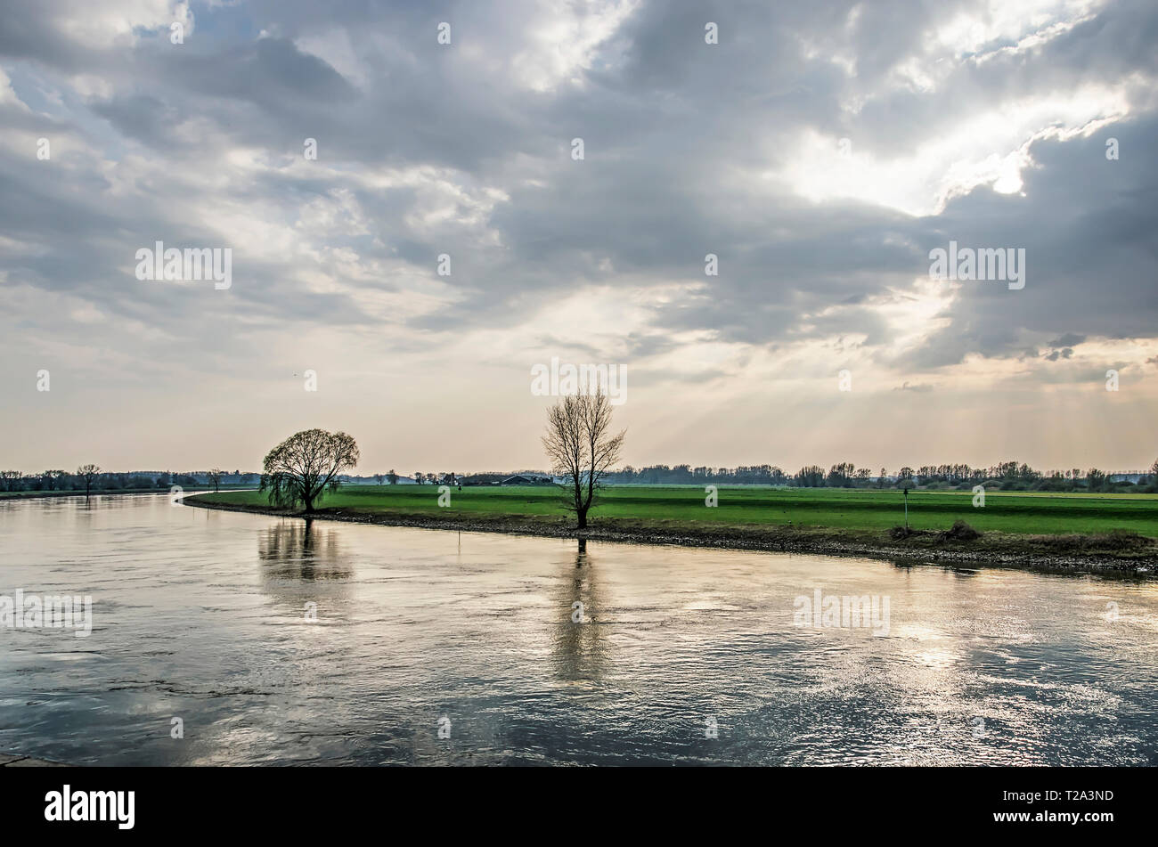 Looking upstream at the IJssel river from the waterfront of the town of Doesburg, The Netherlands under a dramatic sky on an afternoon in springtime Stock Photo