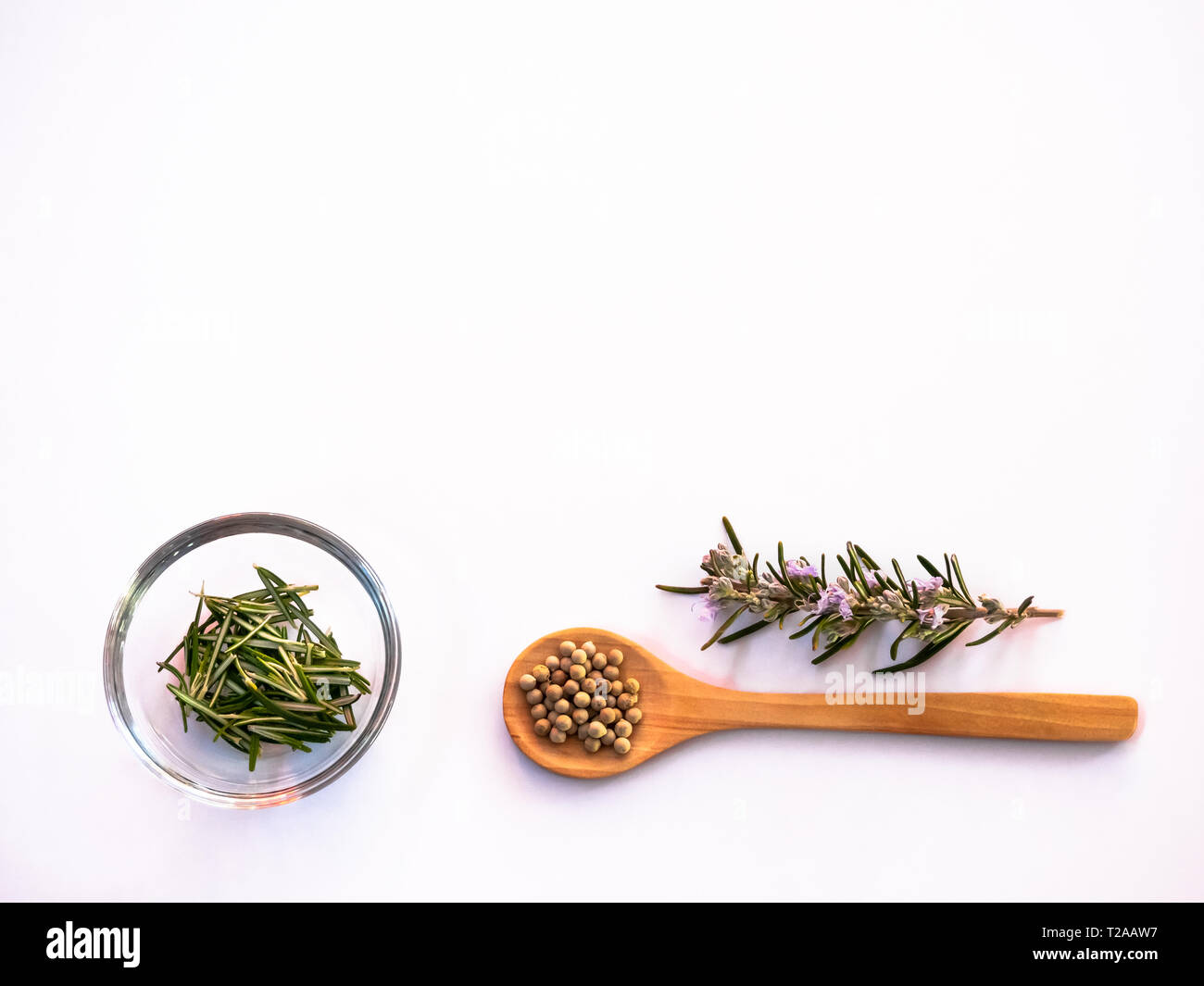 Wooden spoon with white peppercorns and rosemary on a wjote background Stock Photo