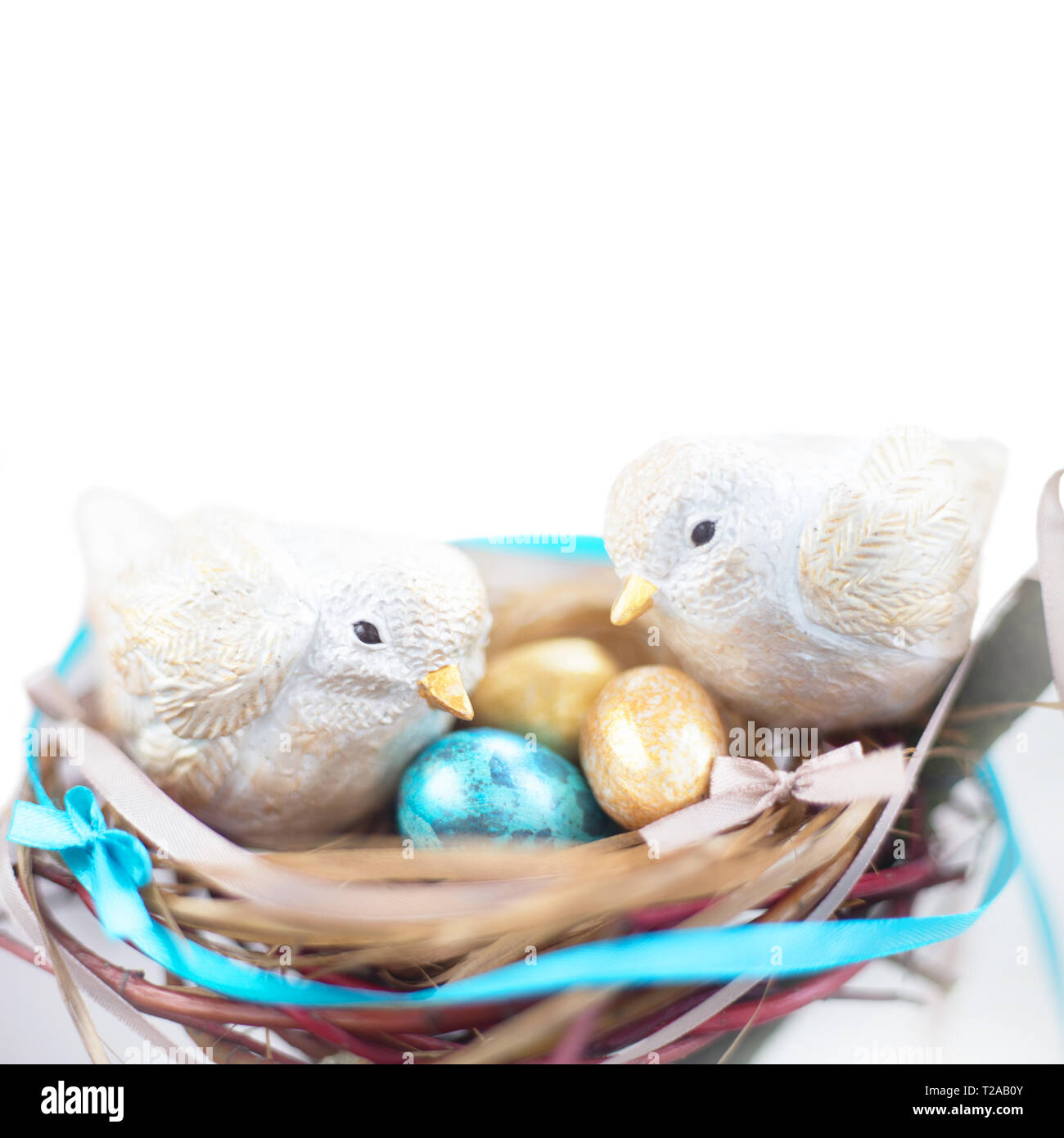 Two cute handmade small easter birds and their golden eggs in nest , parenting , adoption , care concept . Isolated on white background , copy space f Stock Photo