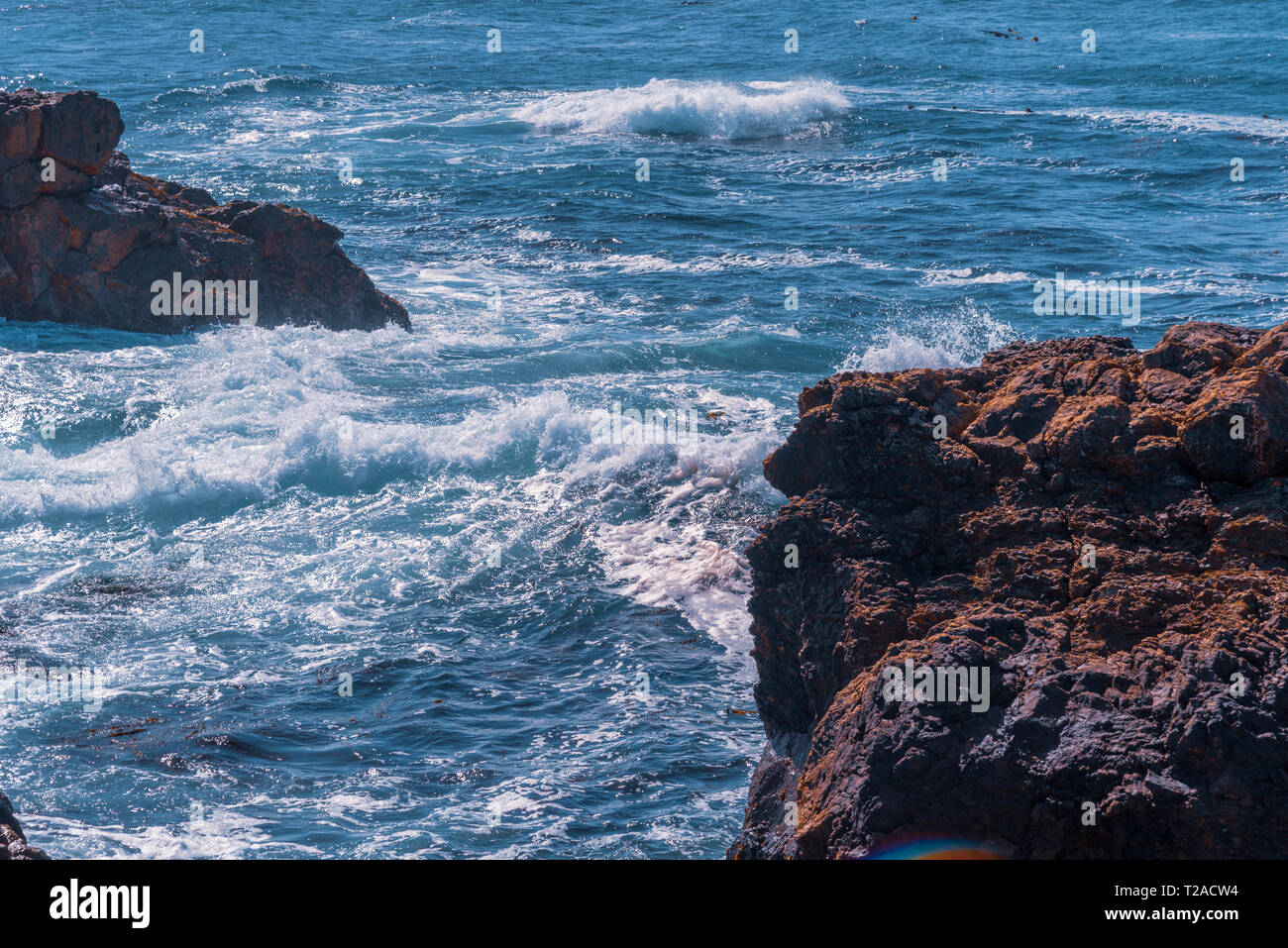 Blue ocean with waves breaking onto rocks. Stock Photo