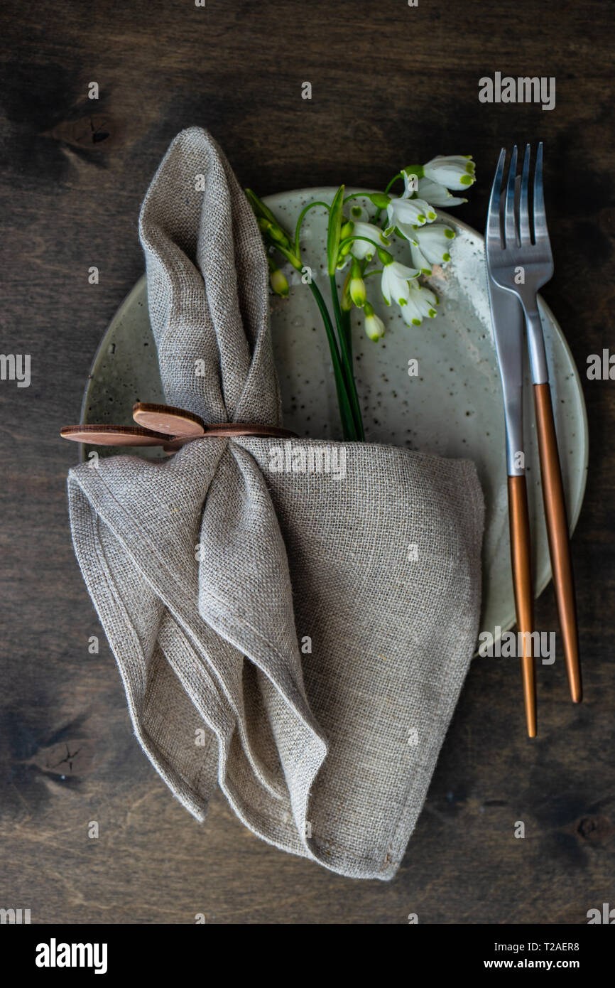 Feastive table setting for holiday Easter dinner decorated with spring snowdrop flowers on rustic table with copy space Stock Photo