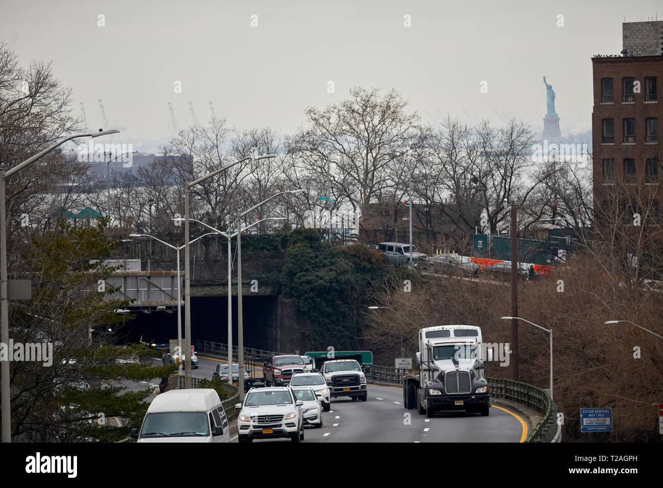 Traffic exiting Brooklyn bridge with the statue of Liberty behind, Manhattan, New York at night Stock Photo