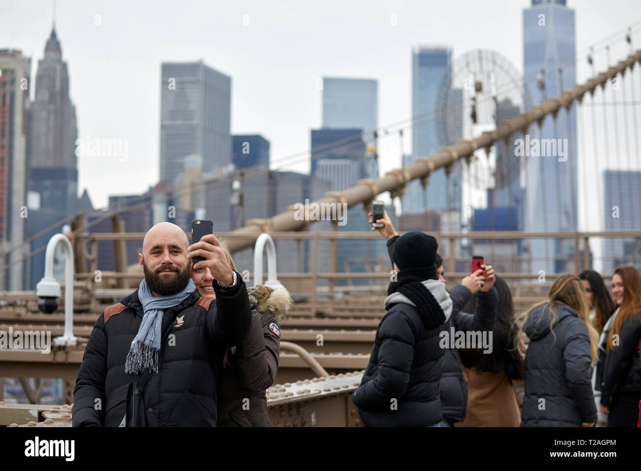 Tourists taking selfies on Brooklyn Bridge Manhattan, New York at night ...