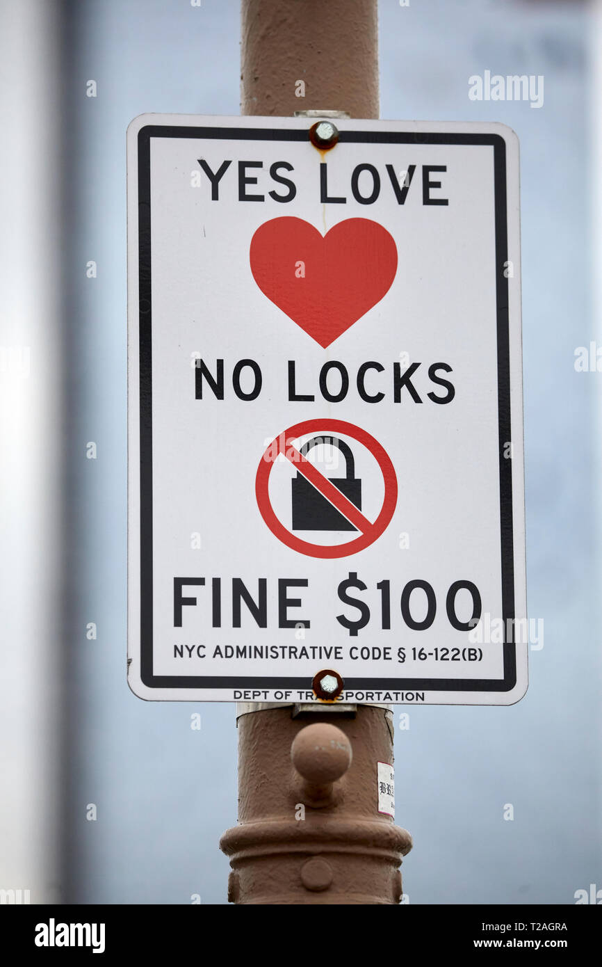 No Padlock fine sign warning romantic couple against fixing locks to the Brooklyn Bridge  Manhattan, New York at night Stock Photo