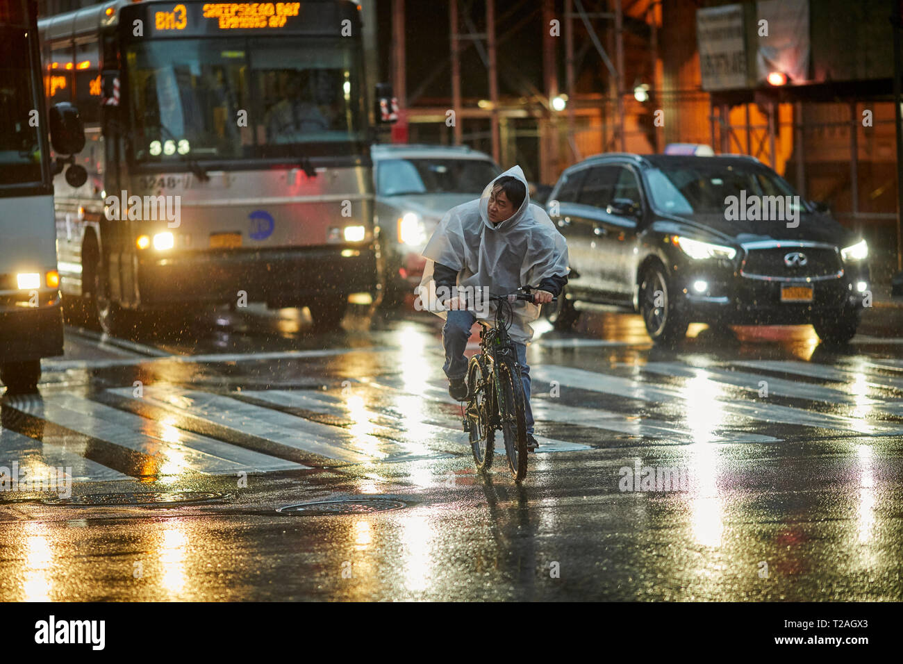waring a rain mac poncho waring cyclist on  8th Avenue Manhattan, New York Stock Photo