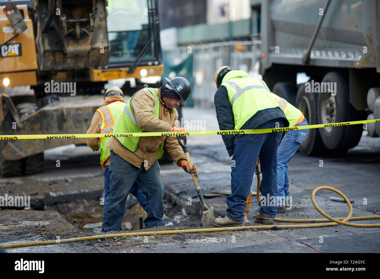 Midtown Manhattan, New York construction workmen digging a hole in the road Stock Photo