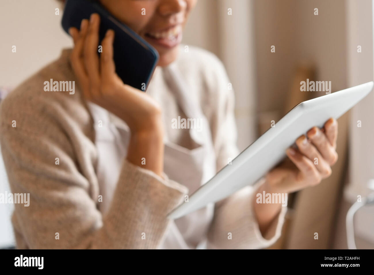 Young woman using digital tablet while taking phone call Stock Photo