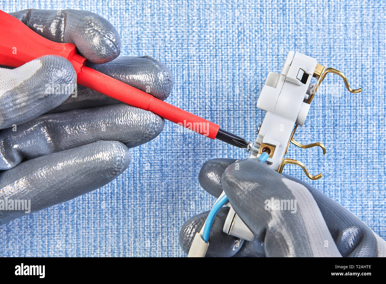 Installing wall plug socket, twisting screw in new outlet with