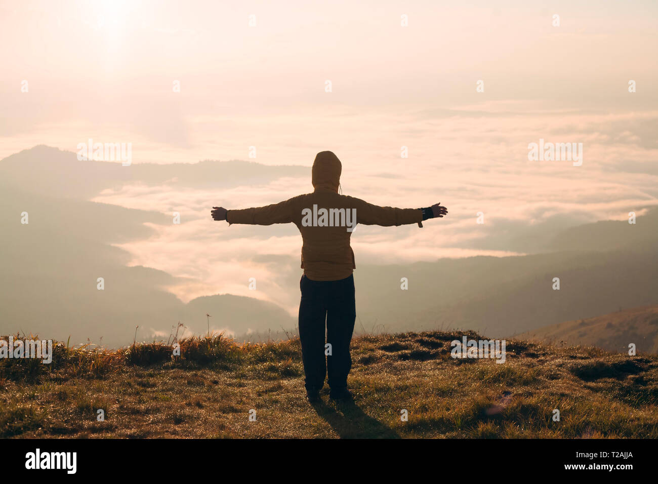 Man with arms outstretched in the Carpathian Mountain Range at sunrise ...
