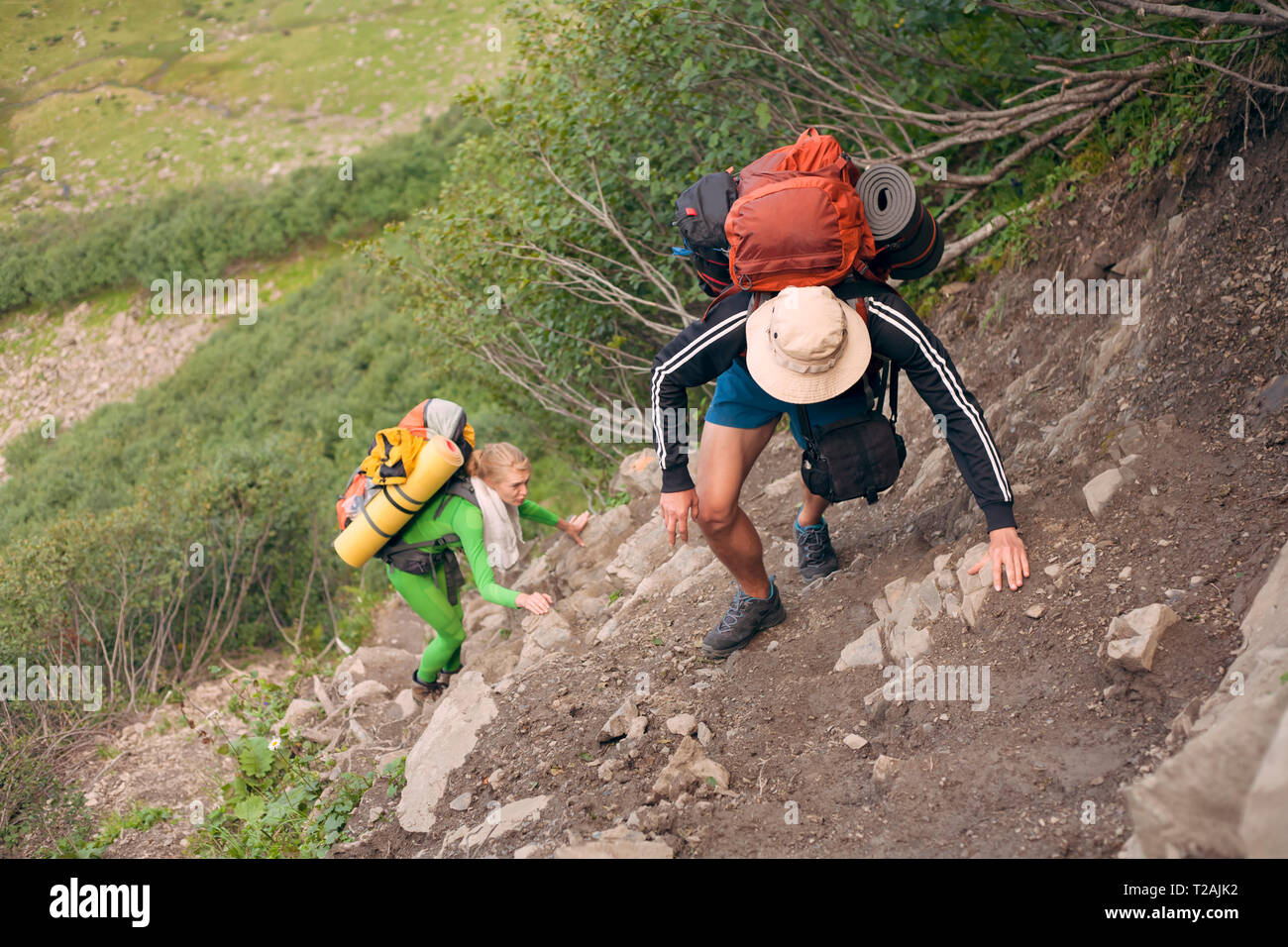 Hiking couple climbing hill Stock Photo - Alamy