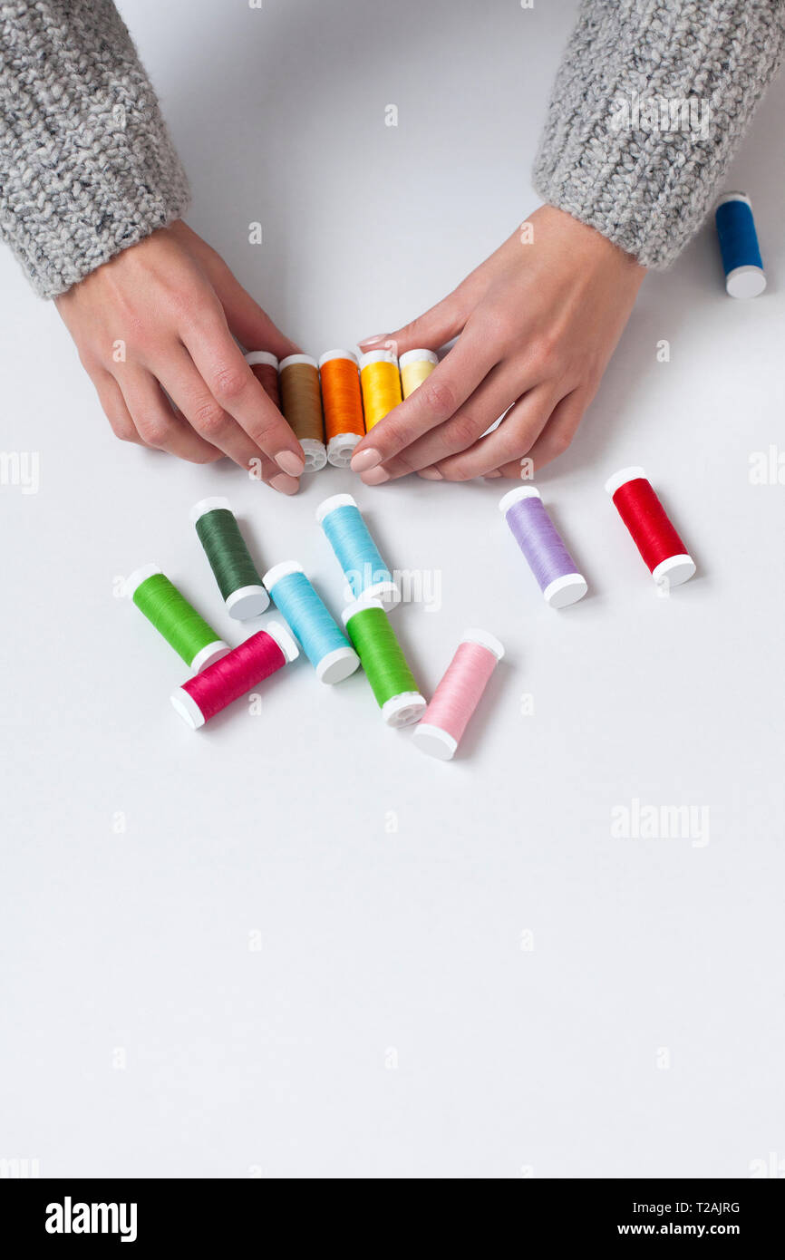 Woman's hands organizing colorful spools of thread Stock Photo - Alamy