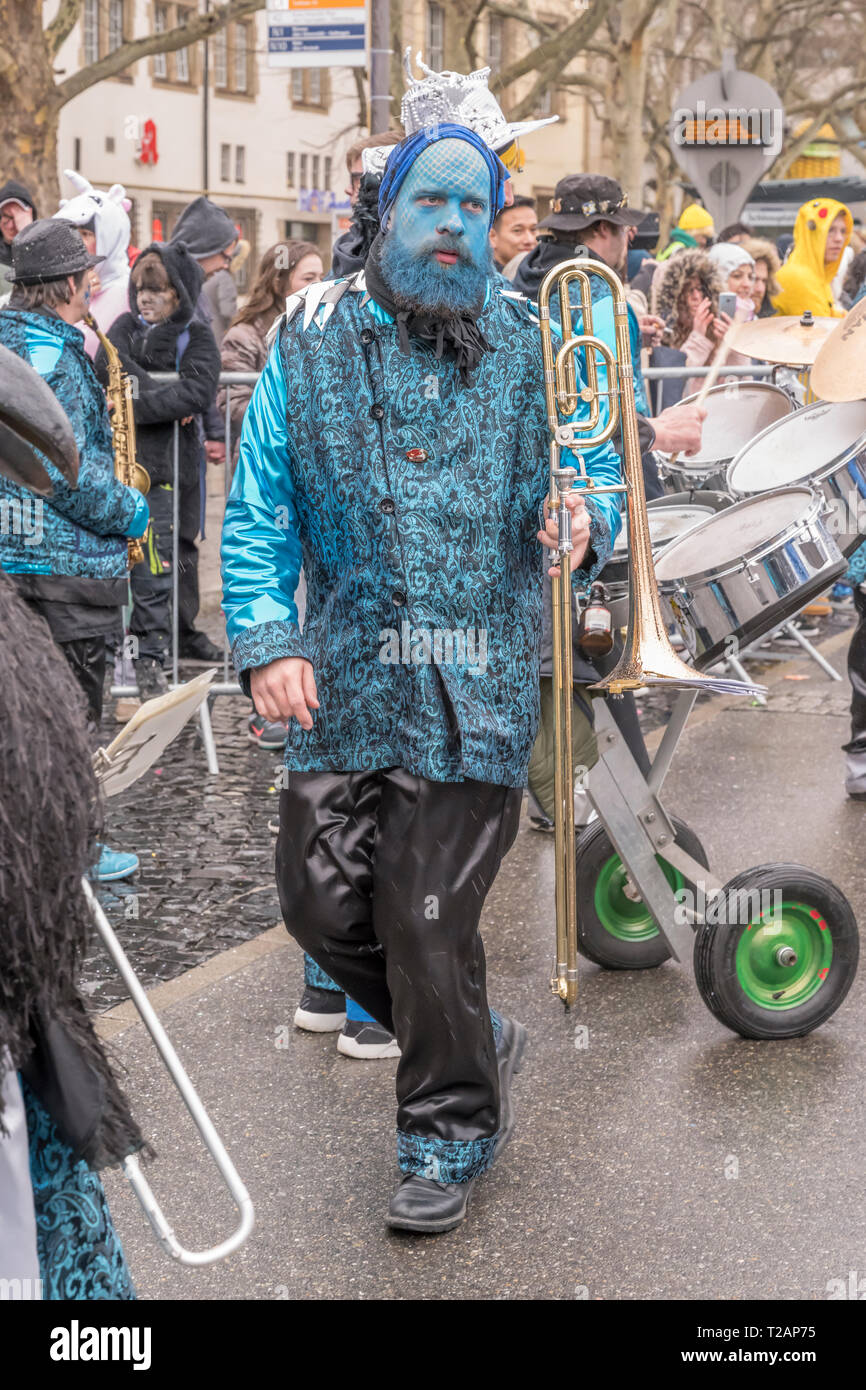 STUTTGART, GERMANY - MARCH 5: dancing dressed up blu trombone player of marching band in parade under light rain.  Shot at  Carnival parade in city ce Stock Photo