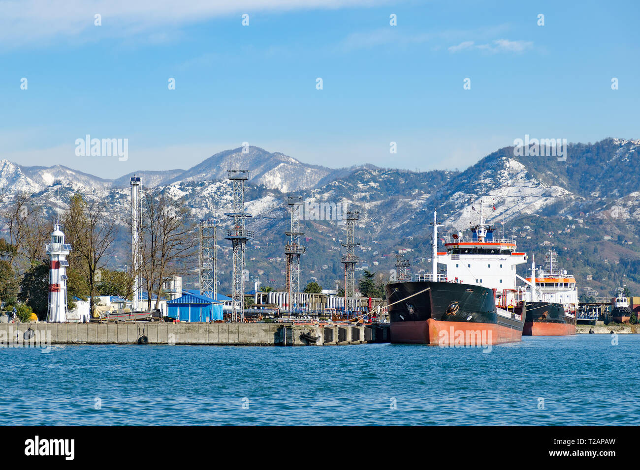 Port view - ships in the harbor, a lighthouse, snowy mountains in the background. Georgia, Batumi. Stock Photo