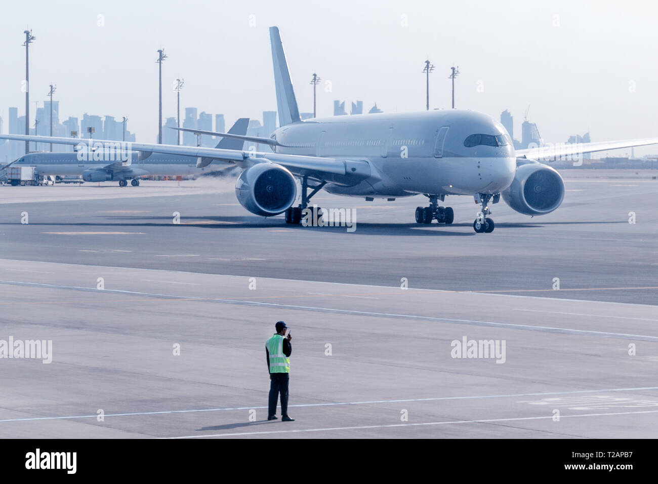 Ground crew manage the movement of airplane at the airport. Aircraft is taxiing to the parking place by Aviation Marshall. Doha, Qatar. Stock Photo