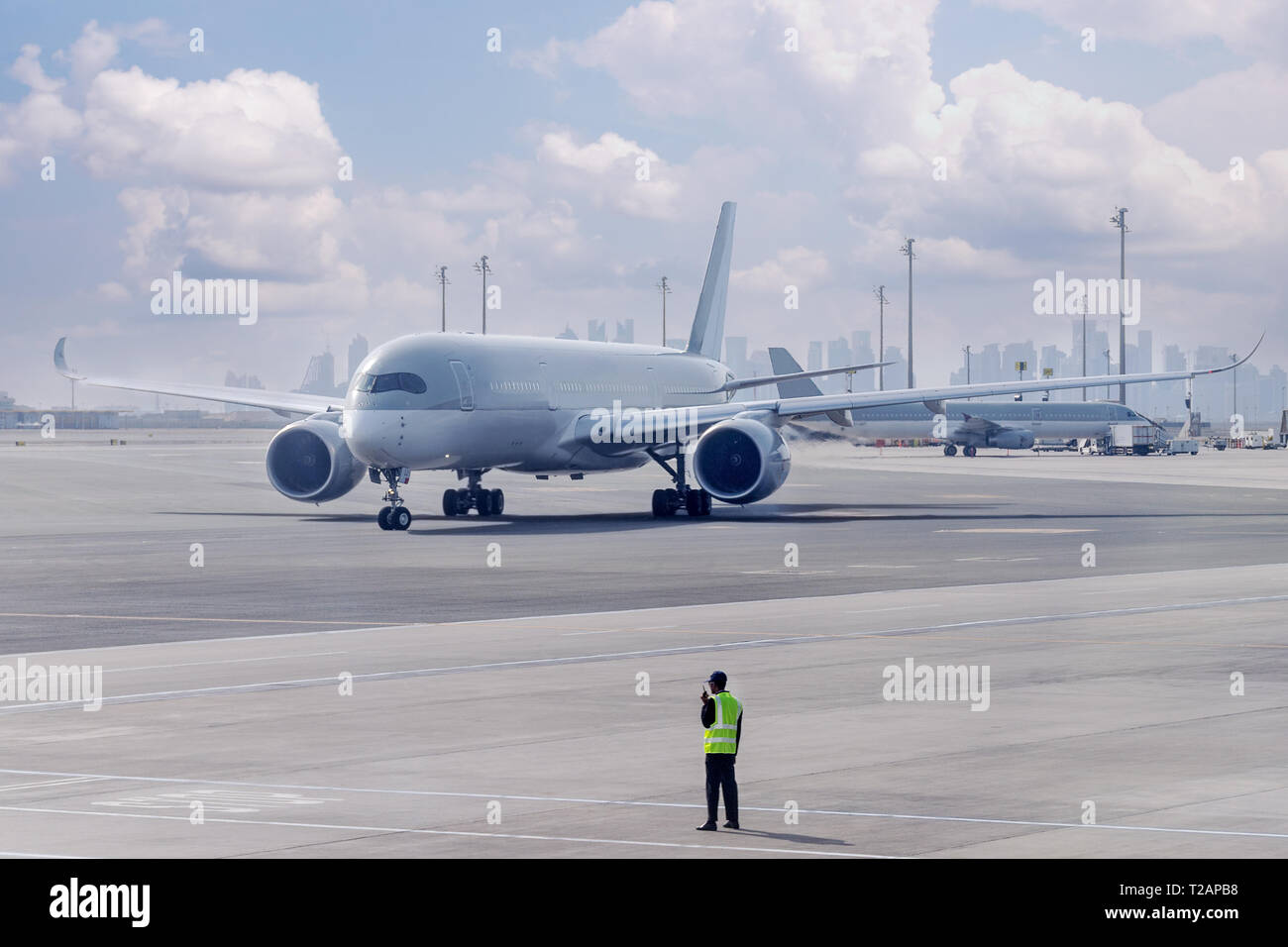 Crew manage the movement of airplane at the airport. Aircraft is guided by ground staff to the parking place. Doha, Qatar. Stock Photo
