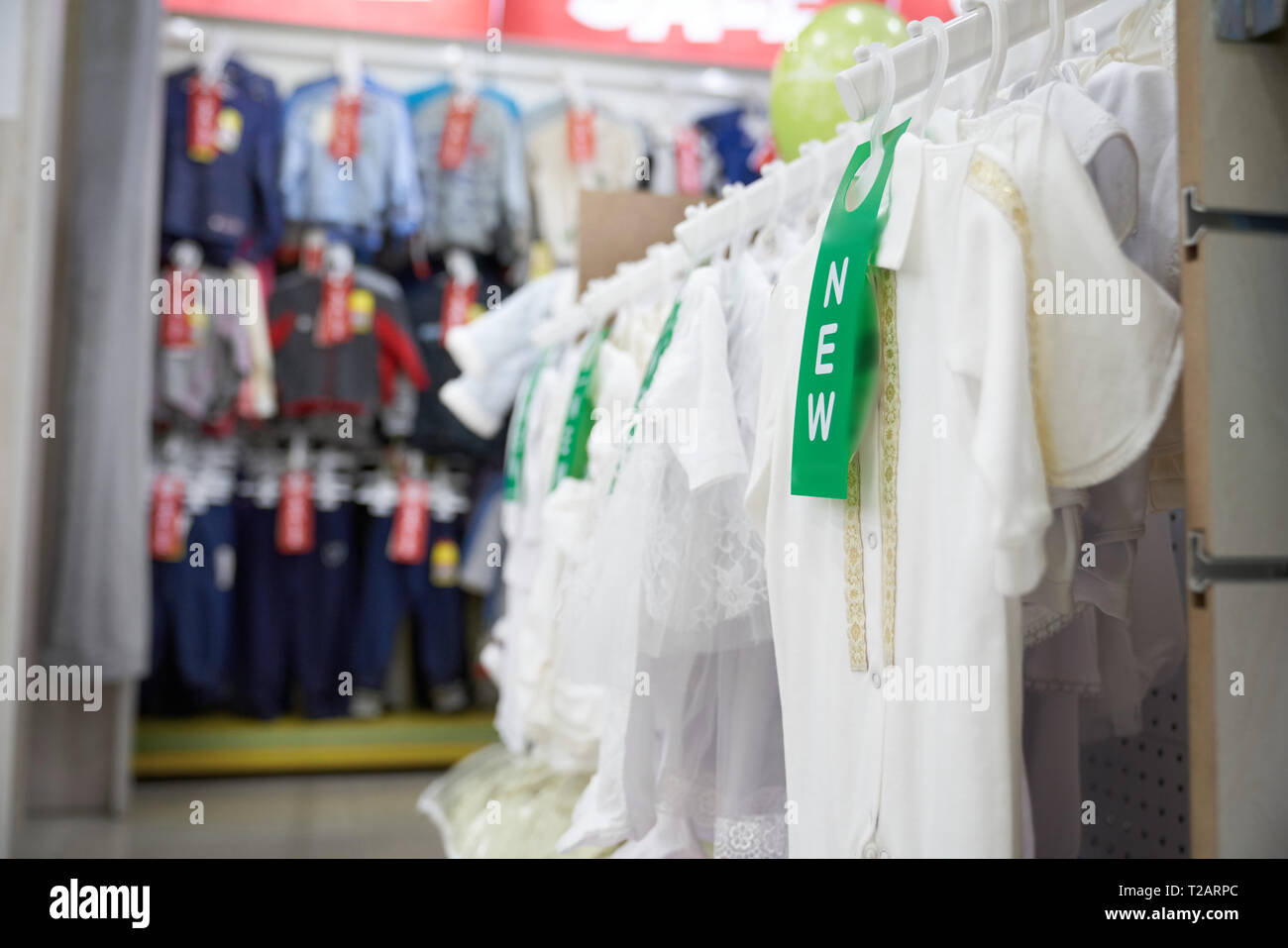 Big choice of stylish, modern clothing in fashionable department store. White blouses on t shirts on hangers. New clothes for girls and boys in shoppi Stock Photo